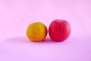 Orange and apple isolated on the pink scene or pink background