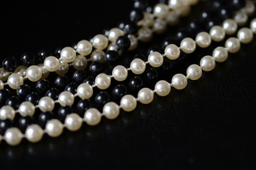 Fragment of a necklace of black and white beads on a black background close-up. Fashion background
