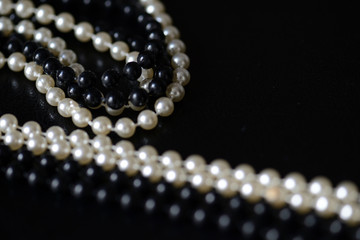 Fragment of a necklace of black and white beads on a black background close-up. Fashion background