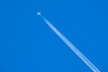 An Airplane and A contrail or A Vapor Trail in The Blue Sky, 青空に浮かぶ飛行機と飛行機雲の様子 - obrazy, fototapety, plakaty