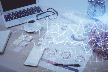 Double exposure of graph and financial info and work space with computer background. Concept of international online trading.