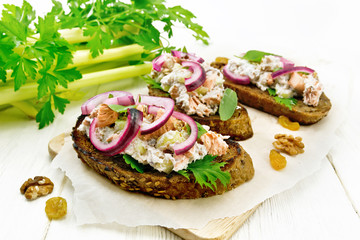 Bruschetta with fish and curd on light wooden board