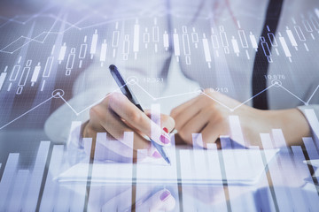 Double exposure of hands making notes with forex chart huds. Stock market concept.