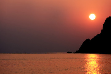 orange sky and sunset on the sea near the cave or mountain