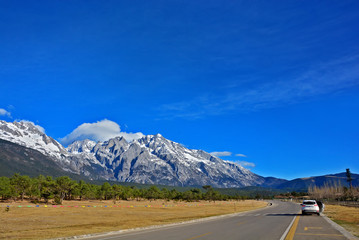 Road in the middle of natural mountain landscape with a van and car on the road with blue sky background