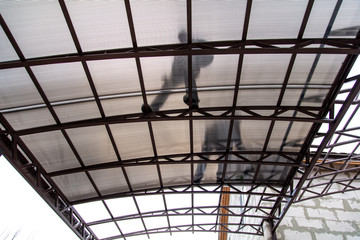 A worker mounts a metal canopy in the courtyard of the house