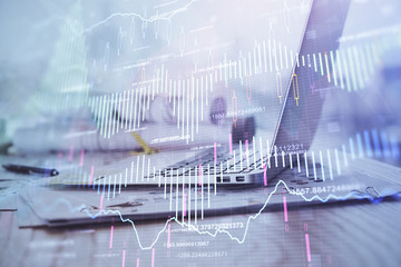 Stock market graph on background with desk and personal computer. Multi exposure. Concept of financial analysis.