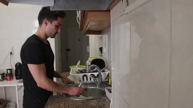Young Man in Black Shirt Turning on Sink and Washing Dishes in