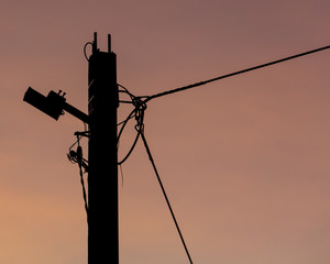 Electric pole with wires on a sunset background
