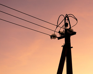 Electric pole with wires on a sunset background
