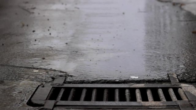 Melted water flows down through the manhole cover on a sunny spring day.