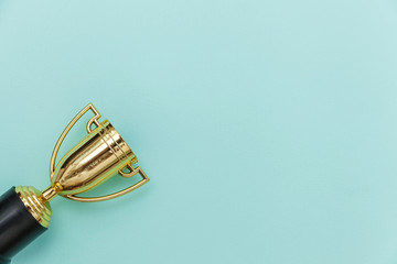 Simply flat lay design winner or champion gold trophy cup isolated on blue pastel colorful background. Victory first place of competition. Winning or success concept. Top view copy space