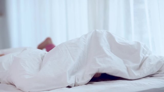 cute siblings in pajamas having fun, hiding under the blanket in bedroom