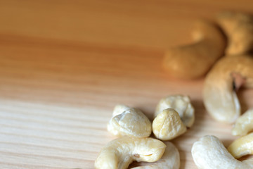 Cashew nuts scattered on a wooden surface close-up. Healthy food background. Brown color toned