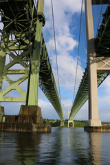 Tacoma Narrows Bridges from water looking up at twin spans and looming columns