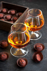 Whiskey or cognac  in  glass with  truffles candy on  dark background