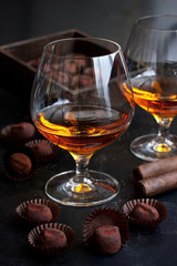 Glass of brandy  or cognac and  chocolate truffles on dark table