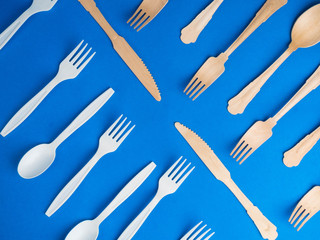 harmful plastic cutlery and eco friendly wooden cutlery. plastic free concept on blue background