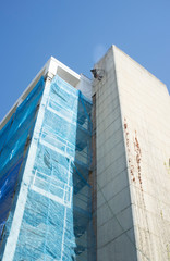 Fototapeta premium Rope access technician washing building facade