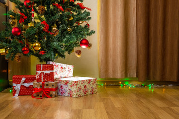 Merry Christmas celebration at home with gift boxes near decorated fir tree with red and gold balls and toys. Living room with garland flashing lights and present boxes. New Year family holidays.