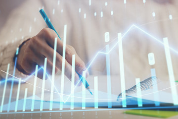 Financial forex graph displayed on hands taking notes background. Concept of research. Double...
