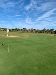 Obraz premium golf green with blue sky and bunkers