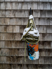 A Buoy With Roap and Topped With Snow Hangs From A Wall