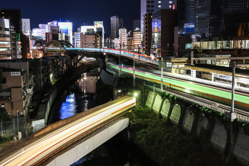 Famous electronic Akihabara district by night with abstract blurry train.