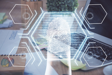 Computer on desktop in office with finger print drawing. Double exposure. Concept of business data security.