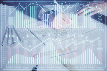 Double exposure of man's hands writing notes of stock market with forex chart.
