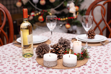 Obraz na płótnie Canvas Set Christmas table for two person in cosy living room with decorated .Christmas tree on the back