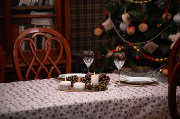 Set Christmas table for two person in cosy living room with decorated .Christmas tree on the back