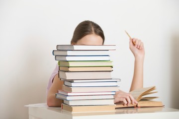 Woman Reading Book Behind Stack Of Books