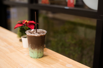 iced mint chocolate drink in plastic glass, put on a wooden table with christmas theme background