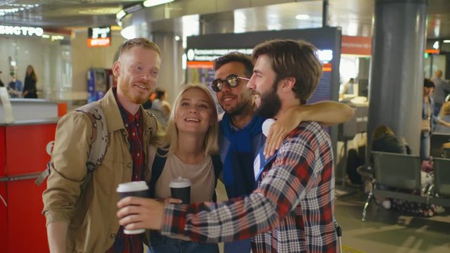 Happy young friends hugging in airport terminal excited about their trip