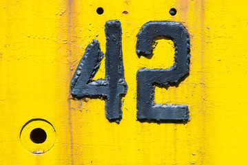 Number 42 on old yellow rusty metal background.