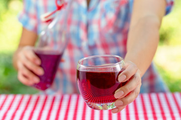 Female hands hold glass with grape or other red juice