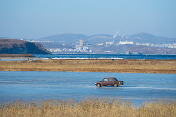 Natural landscape overlooking an old car on a frozen lake.