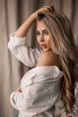 Tender blonde in a white shirt in the studio. Portrait of a blonde