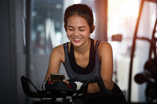 Active girl using smartphone in fitness gym.