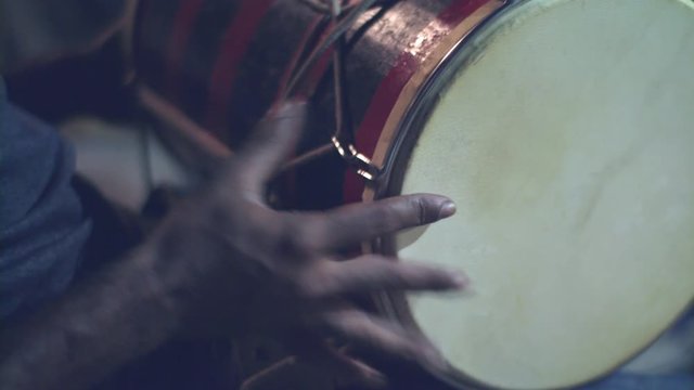 Close up of hands of a black man playing a drum.  Musical instruments and entertainment concept. 