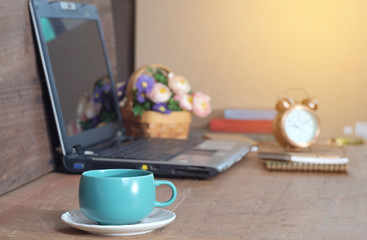Hot coffee mug on office table and laptop working .