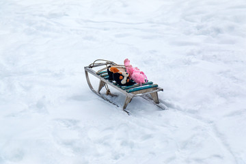 old children sledges are standing in the snow with toys waiting for the owners