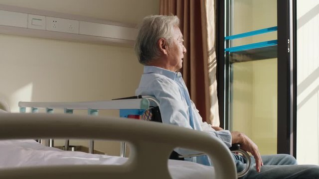 asian old man sitting in wheel chair in nursing home looking happy and content