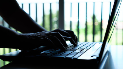 Silhouette hands of hacker or cyber crime typing coding keys on laptop keyboard, Attack signifying...