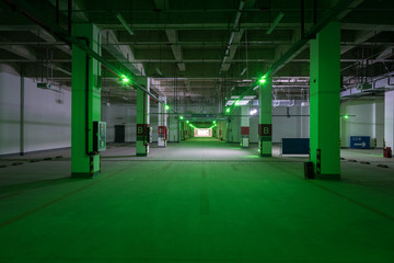 Obraz premium Dim green light perspective of large underground parking space
