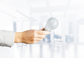 Businesswoman holding in hand glowing light bulb
