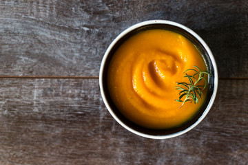 healthy cream of pumpkin soup on a rustic wooden table. Autumn pumpkin cream soup with rosemary herbs and croutons. Copy space