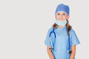 Portrait of young girl in surgeon's costume against gray background