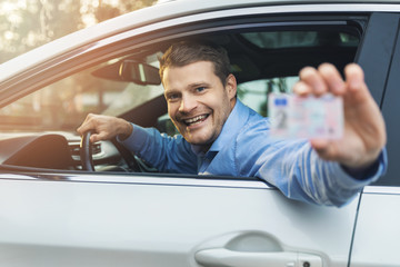 man sitting in the car and showing his driver license out of car window - obrazy, fototapety, plakaty